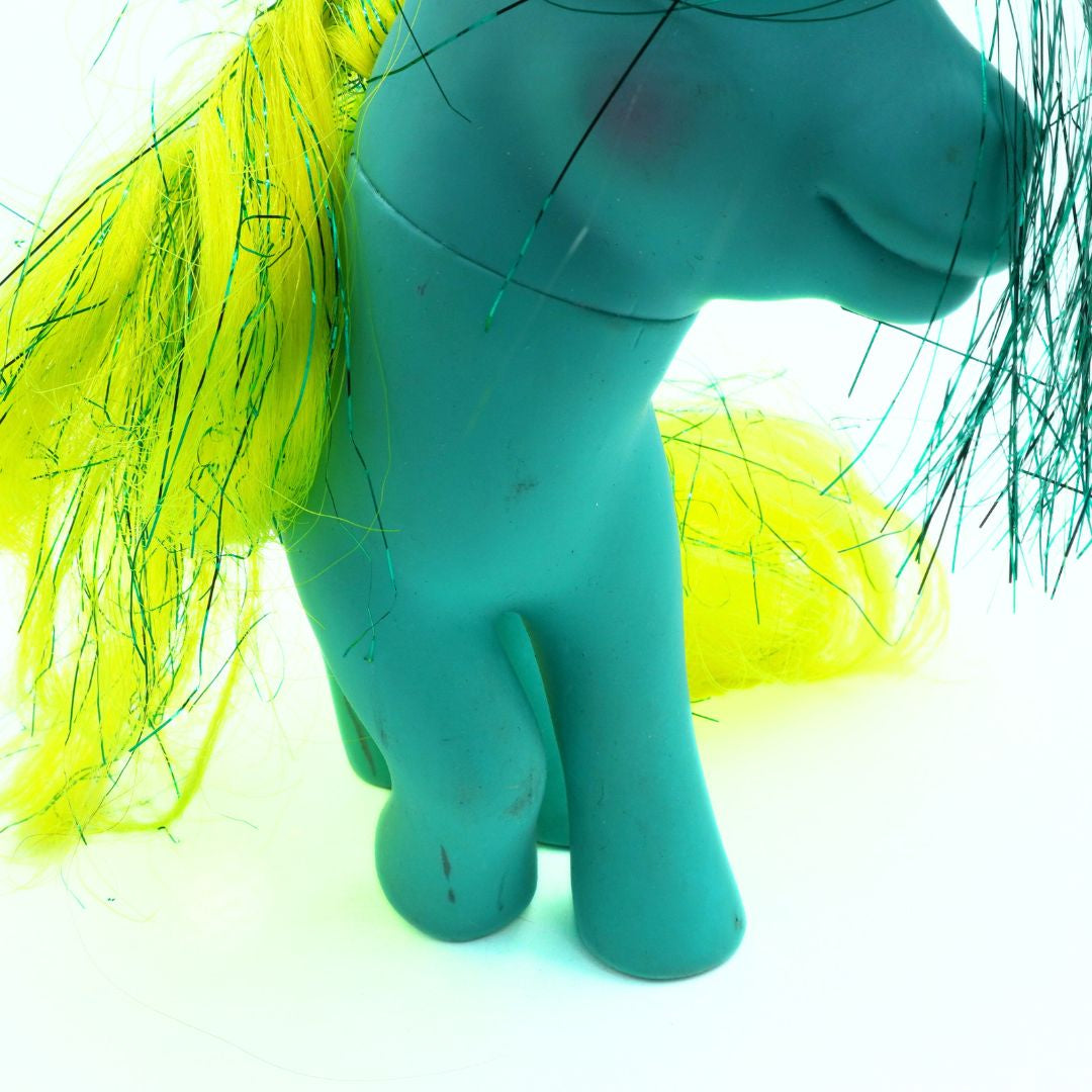 Teal toy figure with yellow hair on a white background