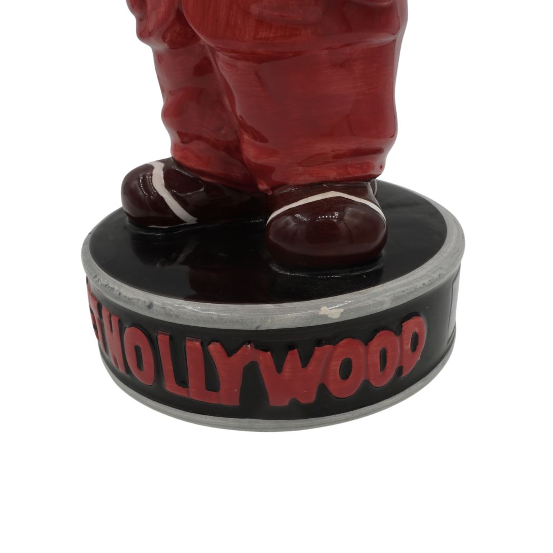 Statue of a person in red pants standing on a circular platform with 'Hollywood' text.