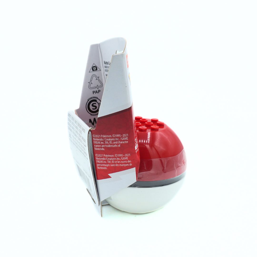 A red and white spherical toy with a small red stud top, standing upright next to its white and red retail packaging on a plain white background.