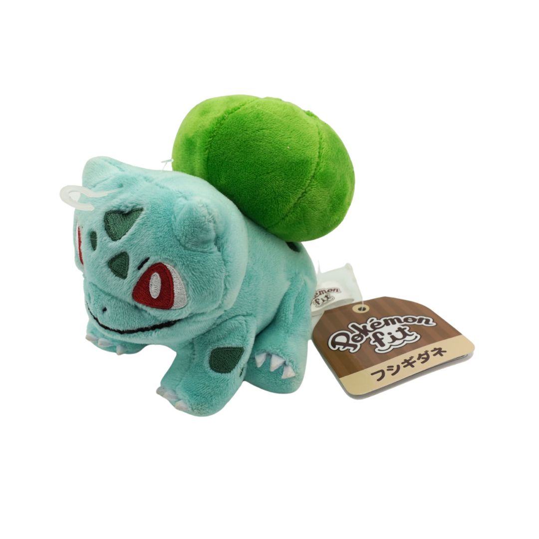 Plush toy of a green and blue creature with a tag on a white background