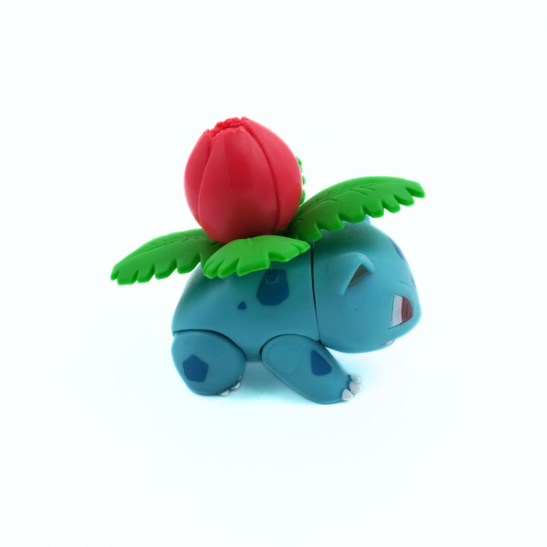 Toy figure of a blue creature with a red flower on its head against a white background