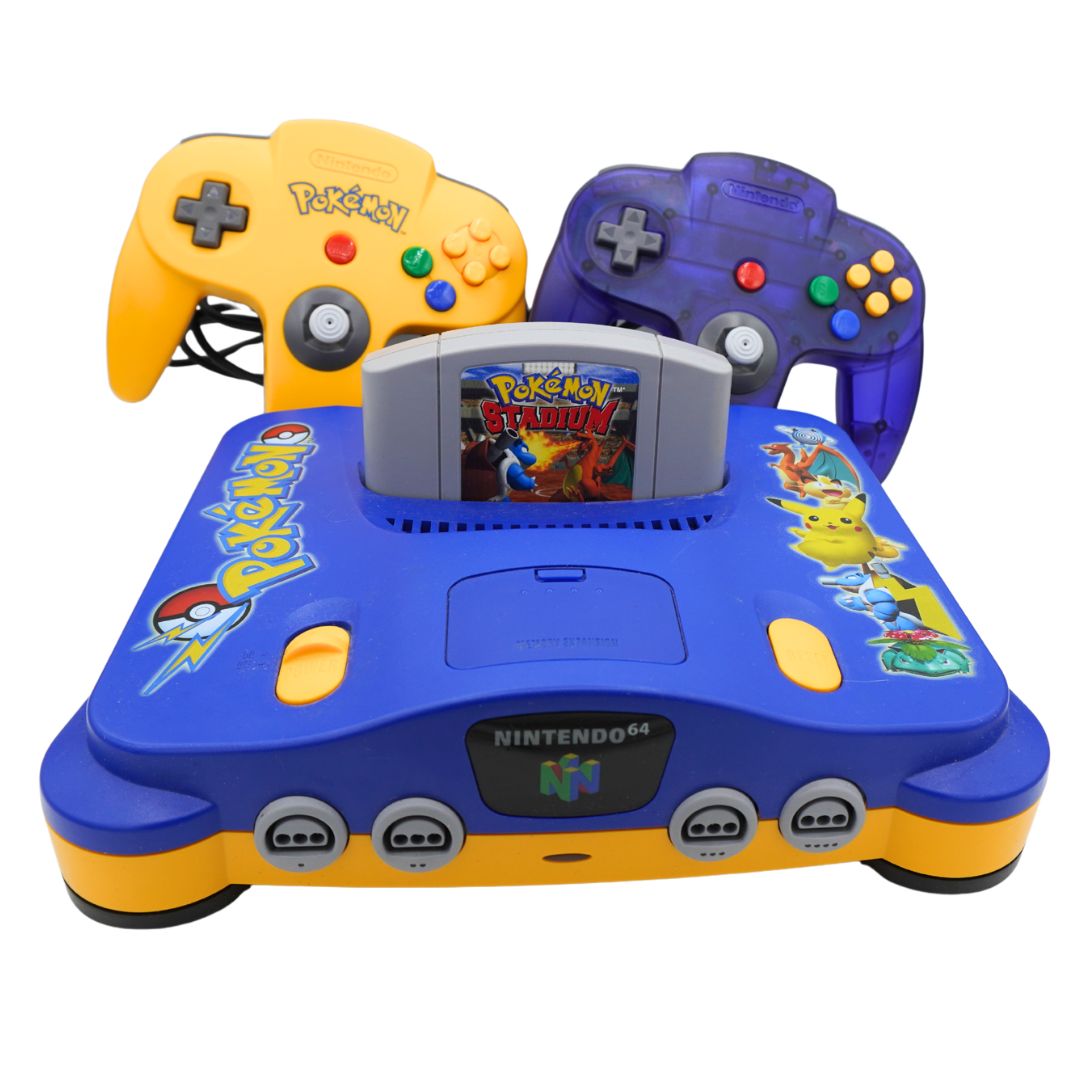 A retro-themed Nintendo 64 console set featuring a blue and yellow Pokémon-themed console in the center, with two game controllers behind it: a yellow Pokémon N64 controller and a translucent purple Pokémon N64 controller. The console has Pokémon and Nintendo 64 branding, and the cartridge insert shows Pokémon Stadium.