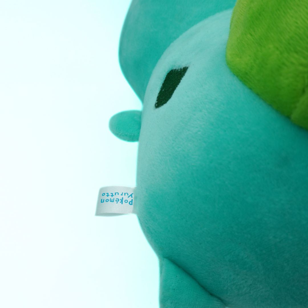 Close-up of a teal plush toy with a green hat on a light blue background