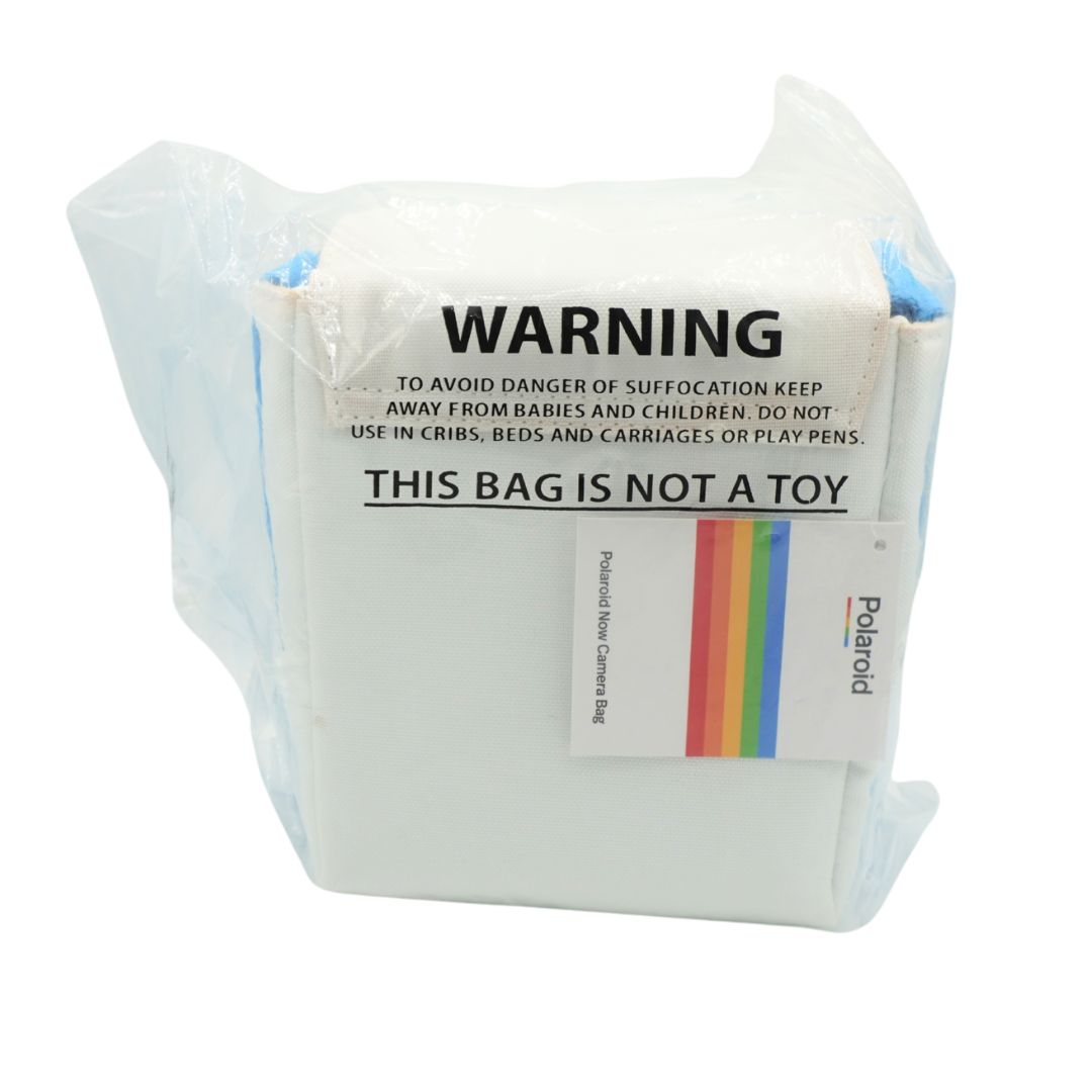A white Polaroid film canister wrapped in a clear plastic protective bag, with a white warning label that reads 'WARNING THIS BAG IS NOT A TOY' and a small rainbow logo.