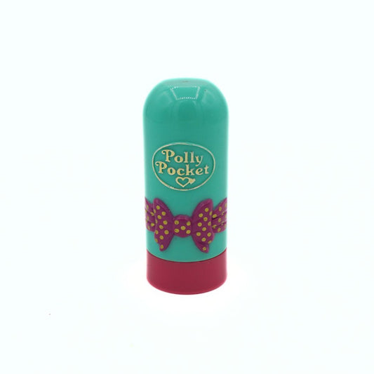 Polly Pocket lip balm stick with a turquoise green body, a pink bow design with gold polka dots, and a dark pink cap, shown on a white background.
