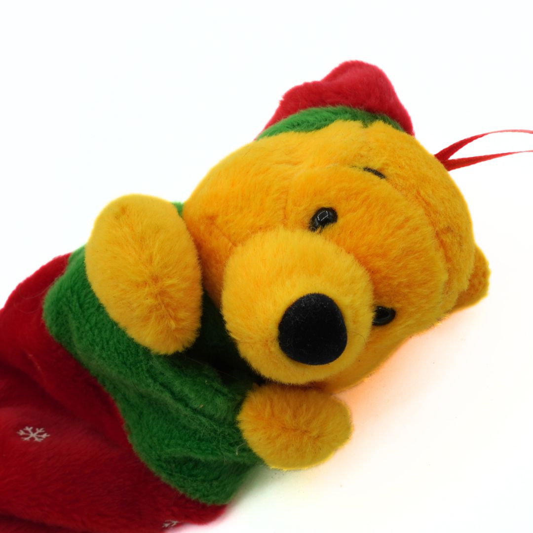 Plush bear toy with a red and green scarf on a white background