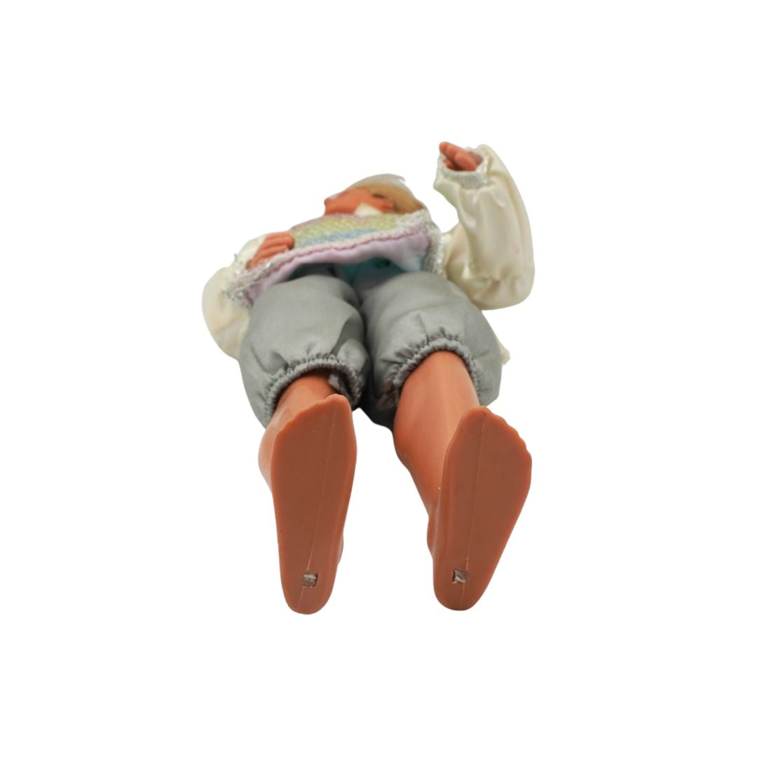 Small figurine of a person lying down with a blanket on a white background