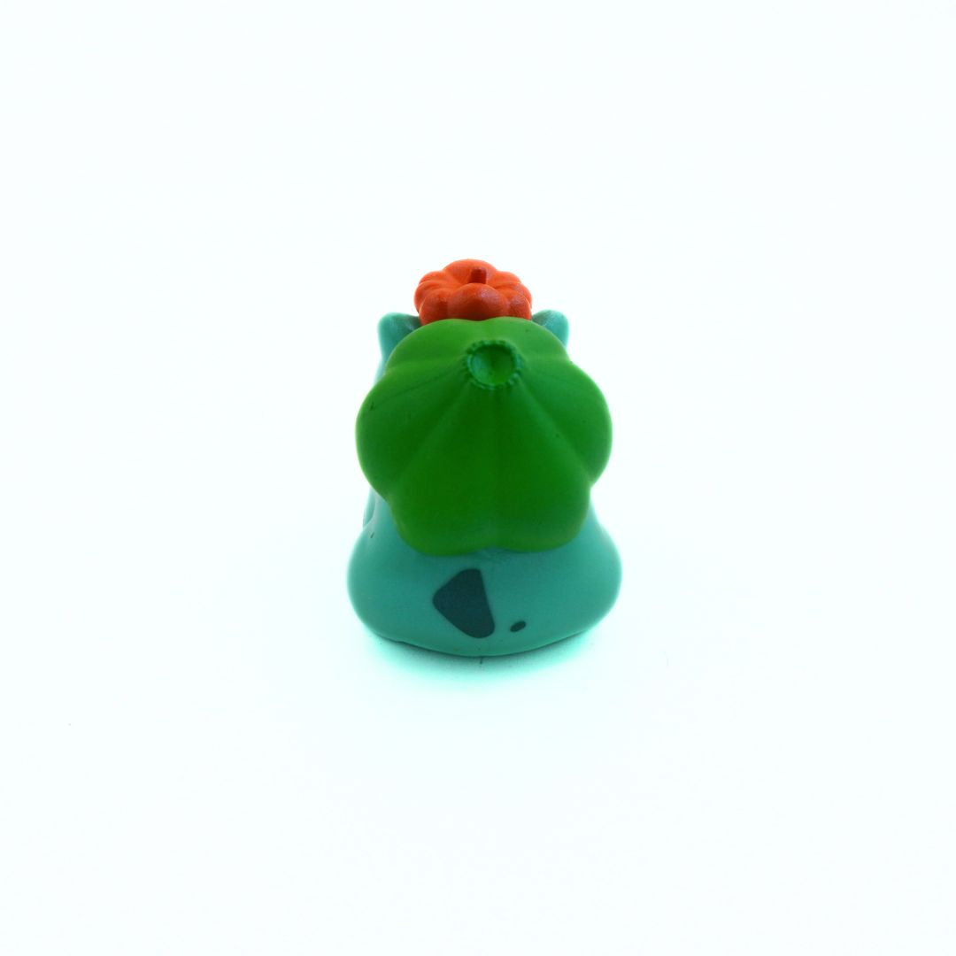 Small green and orange toy figure on a white background