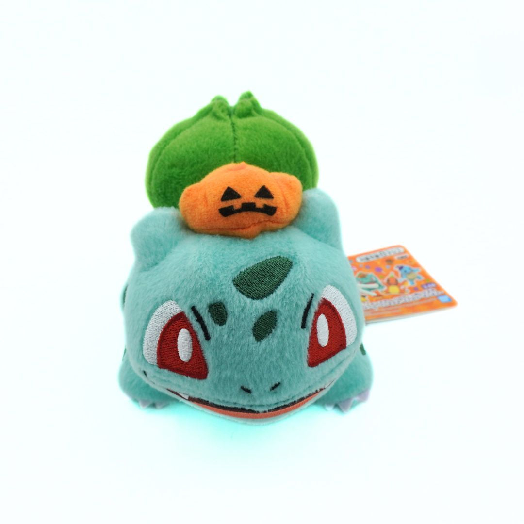 Plush toy of a green creature with a pumpkin on its head, on a white background
