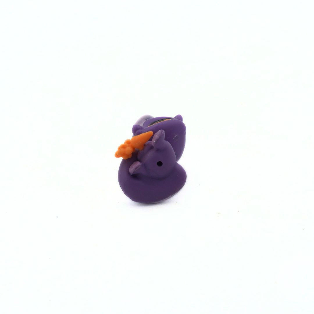 Purple rubber skunk with an orange carrot on a white background