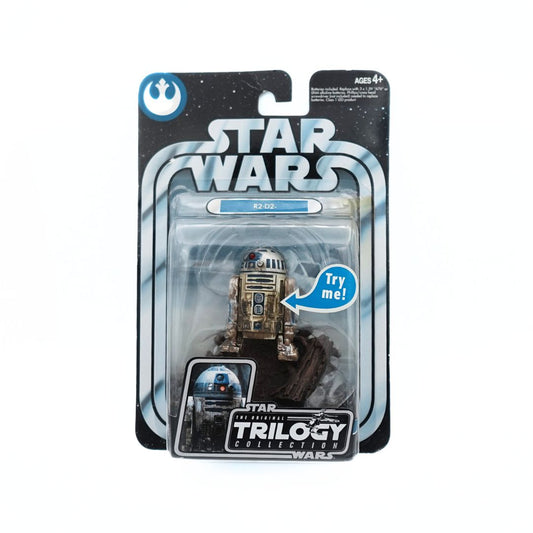 Photo of a 2004 R2-D2 Star Wars Original Trilogy figurine in its packaging, showing the white and blue droid covered in dirt