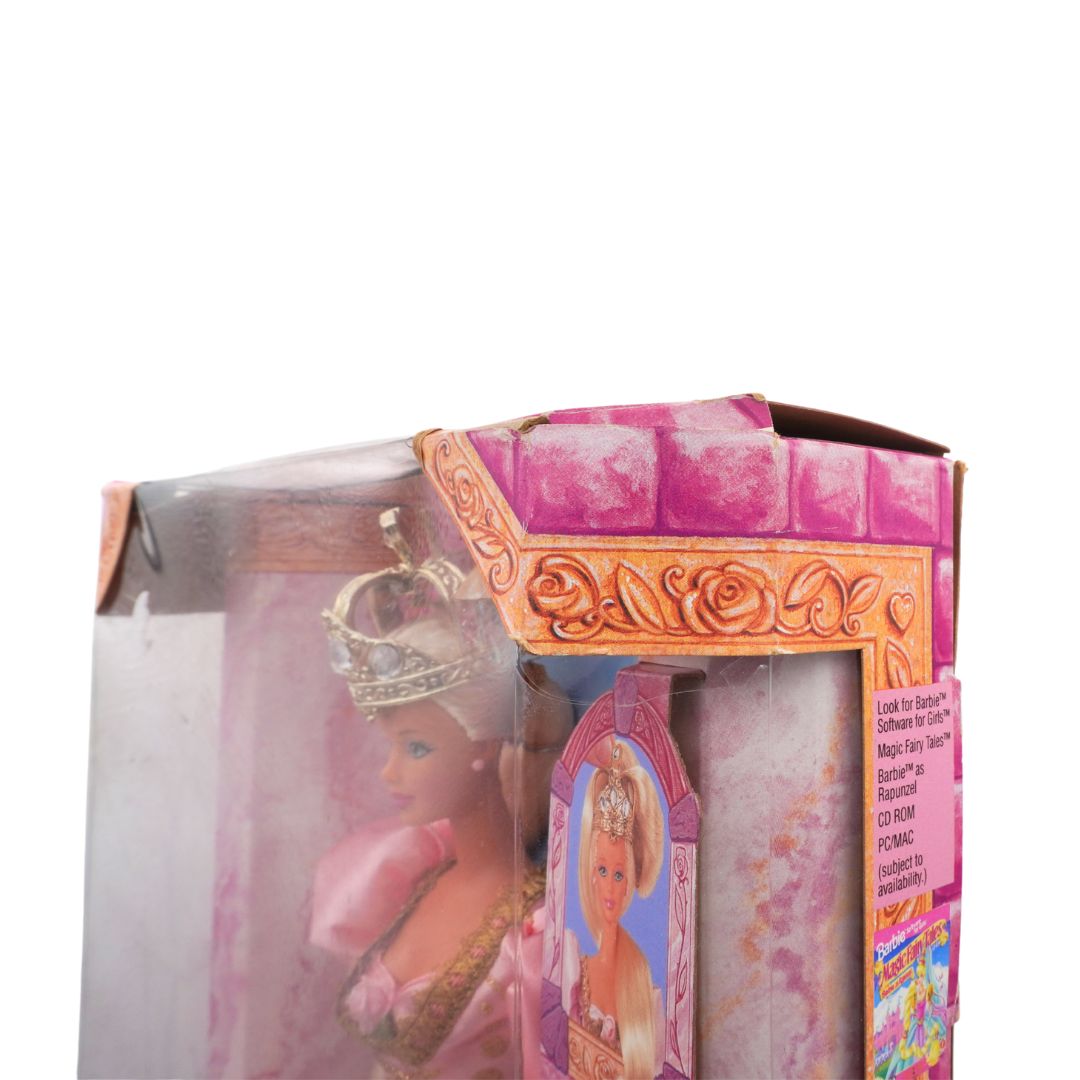 Barbie doll in a pink dress with a crown inside a toy box packaging.
