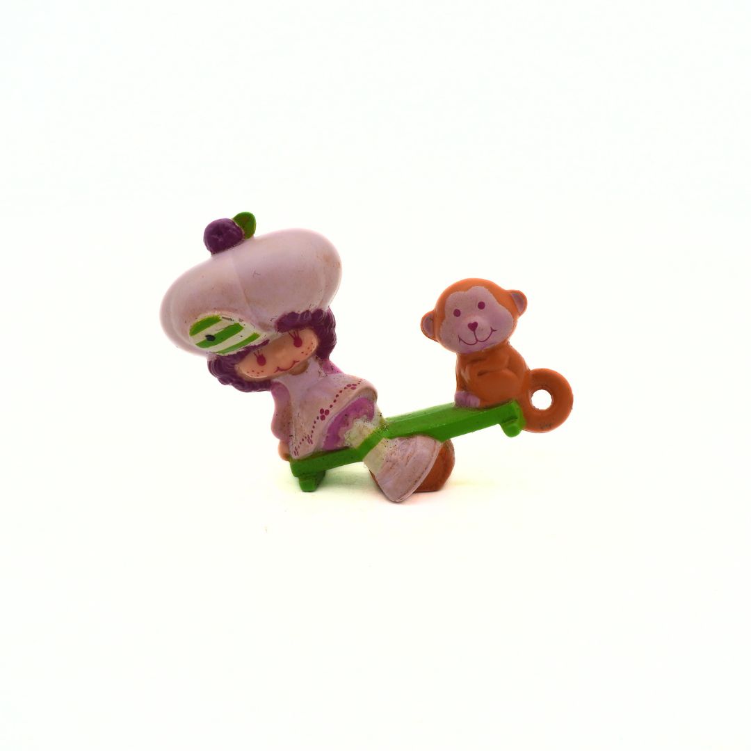 Toy figure of a girl and monkey on a seesaw with a white background