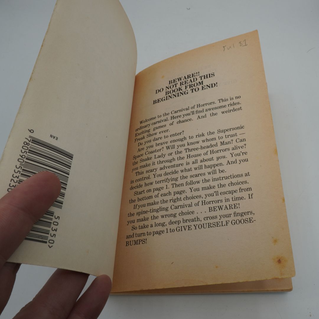 Open book with text and a barcode, held by a hand on a white background