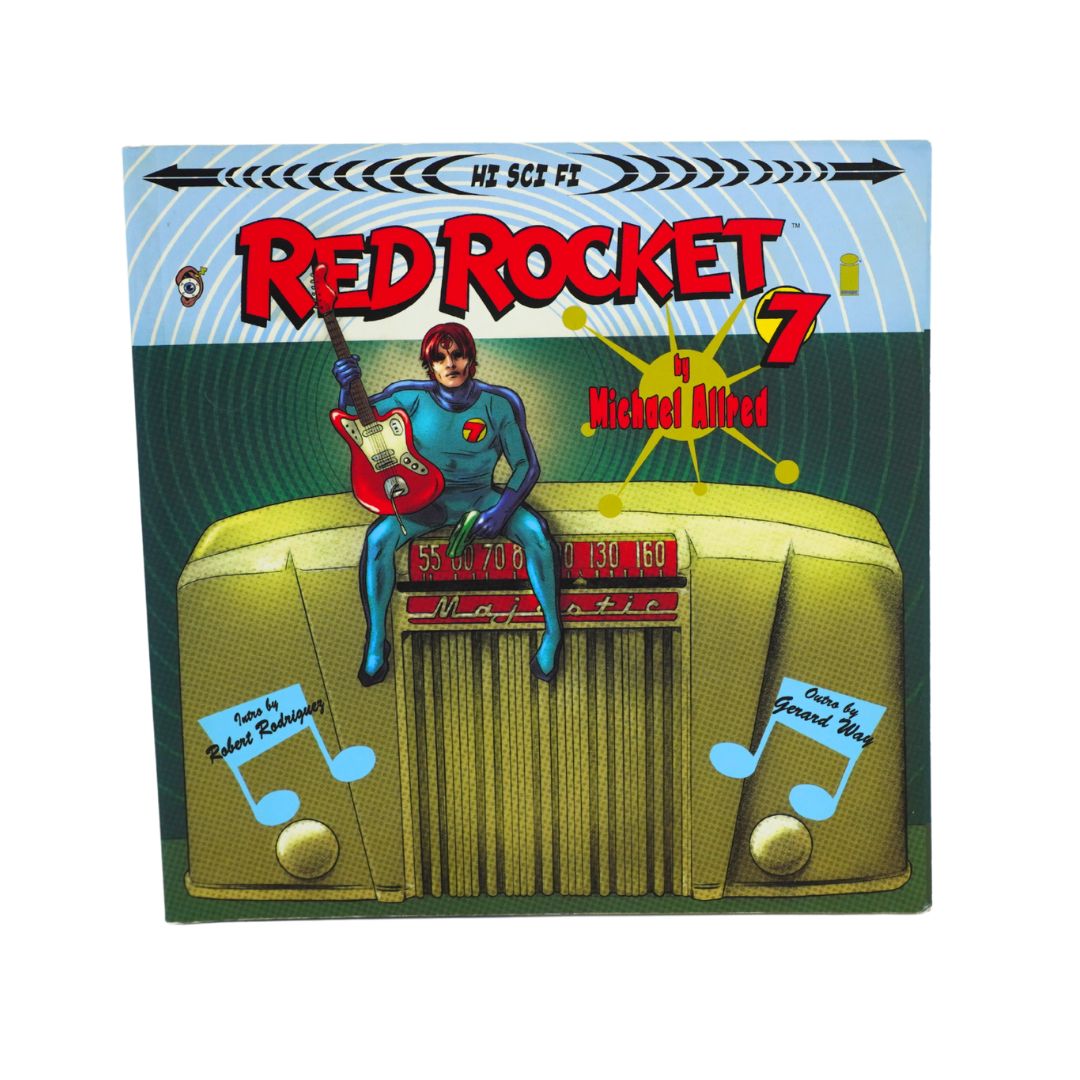 A square illustrated product cover or packaging panel for 'Red Rocket 7' featuring a cartoon figure in a blue suit sitting on a yellow vehicle and holding a red guitar. The title 'Red Rocket 7' is prominent in red text, with additional stylized text and graphic elements on a light blue and green background.