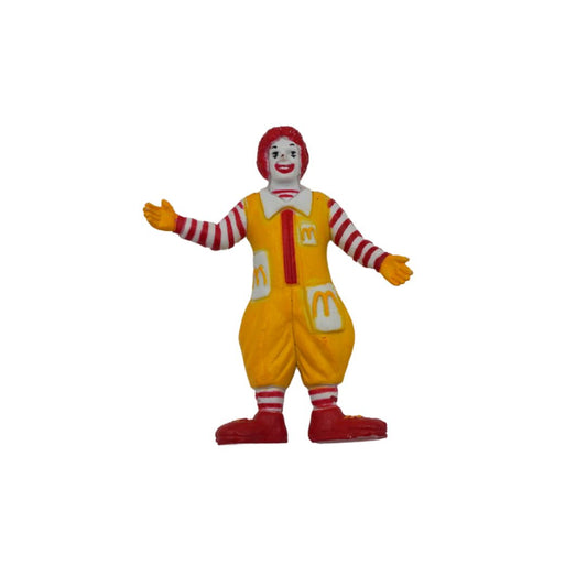 A Ronald McDonald toy figure wearing his signature yellow overalls, red and white striped sleeves and socks, with red shoes and hair, set against a plain white background.