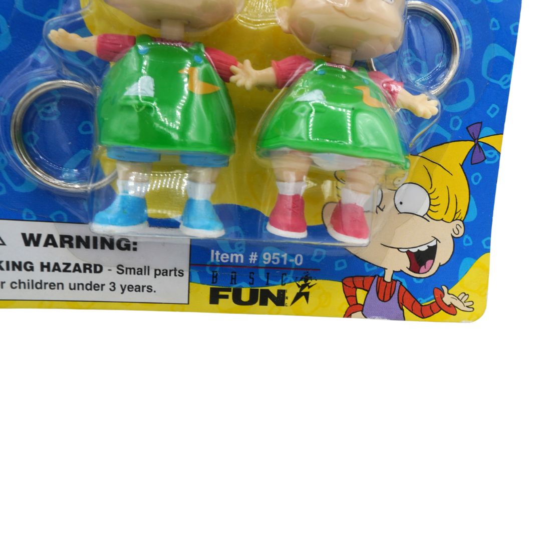 Toy figures in green dresses on a colorful packaging with a warning label.