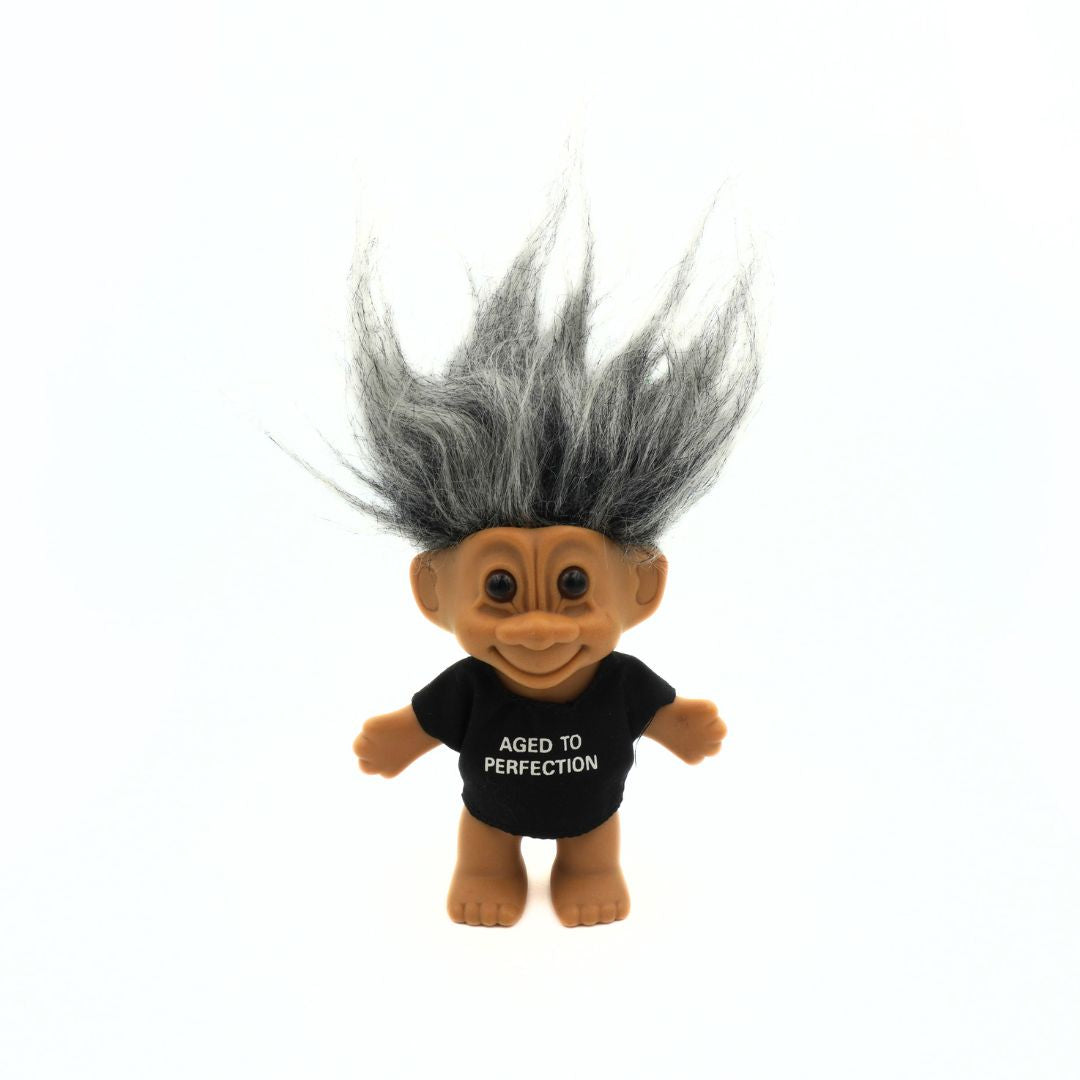 Russ troll toy with gray hair and a black shirt reading 'Aged to Perfection' on a white background
