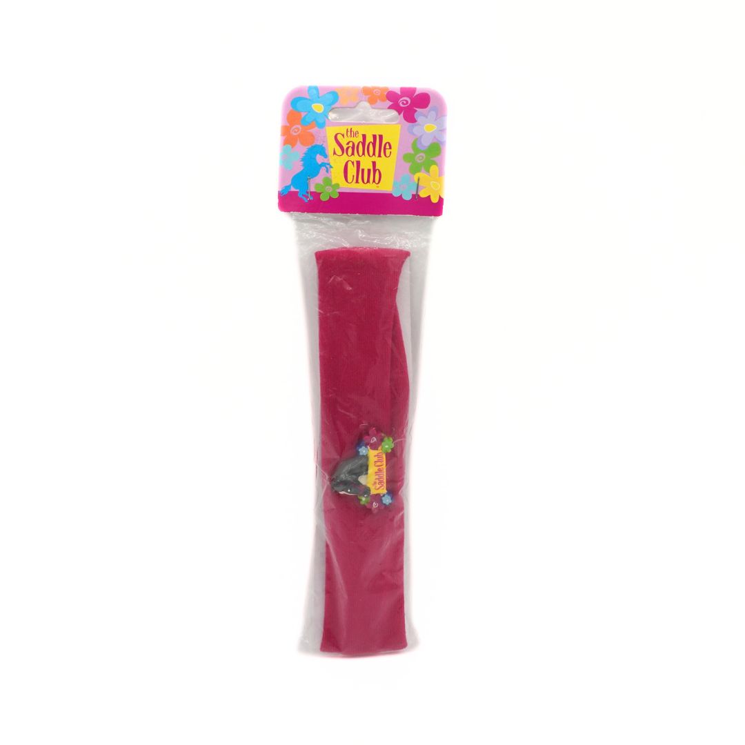Pink headband with 'The Saddle Club' branding on a white background