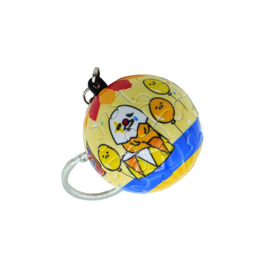 A spherical jigsaw puzzle keychain featuring cartoon characters on a yellow background with blue and orange accents, attached to a silver metal key ring.