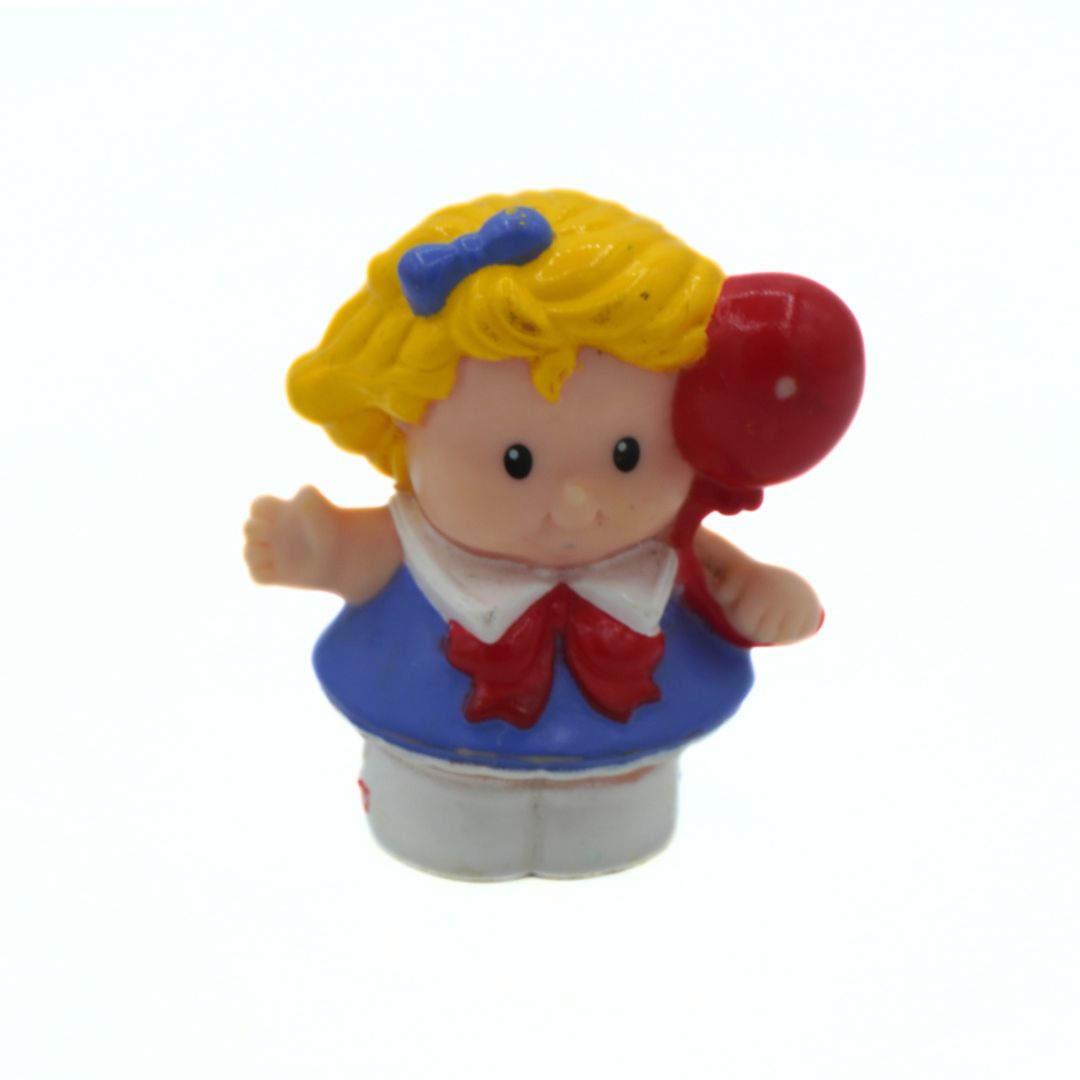 Toy figure with blonde hair, blue bow, red balloon, and blue dress on a white background