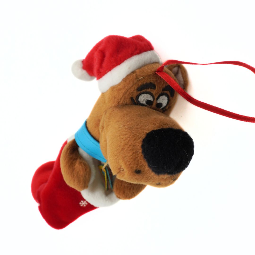 Plush toy of a dog character wearing a Santa hat on a white background
