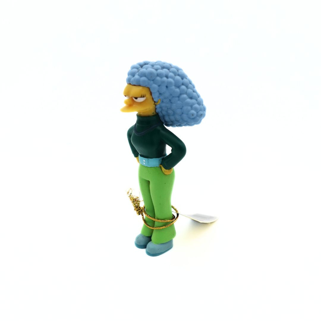 2006 Simpsons figurine of a young Selma Bouvier from the Way We Was collection. She is wearing a dark green shirt and light green pants.
