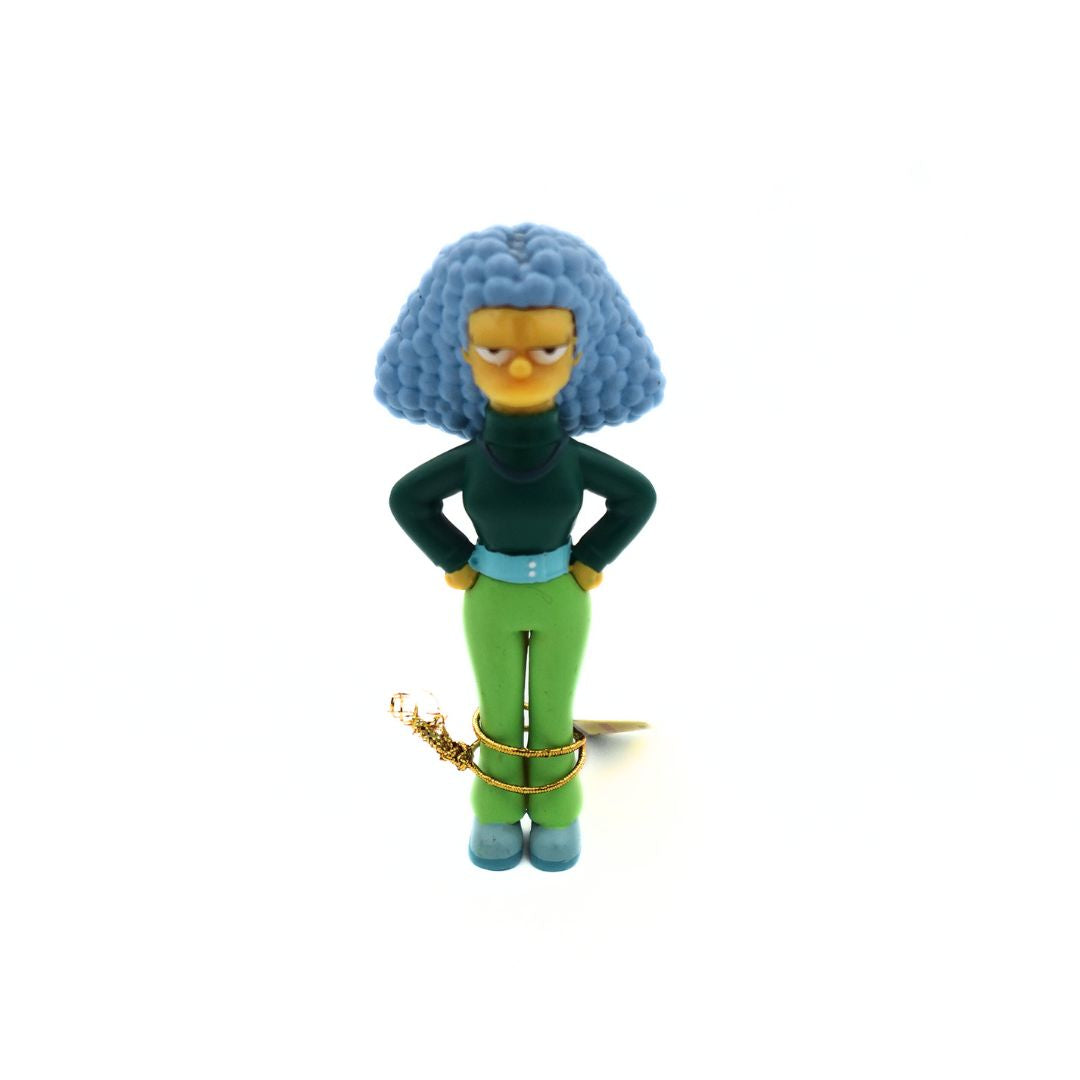 2006 Simpsons figurine of a young Selma Bouvier from the Way We Was collection. She is wearing a dark green shirt and light green pants.