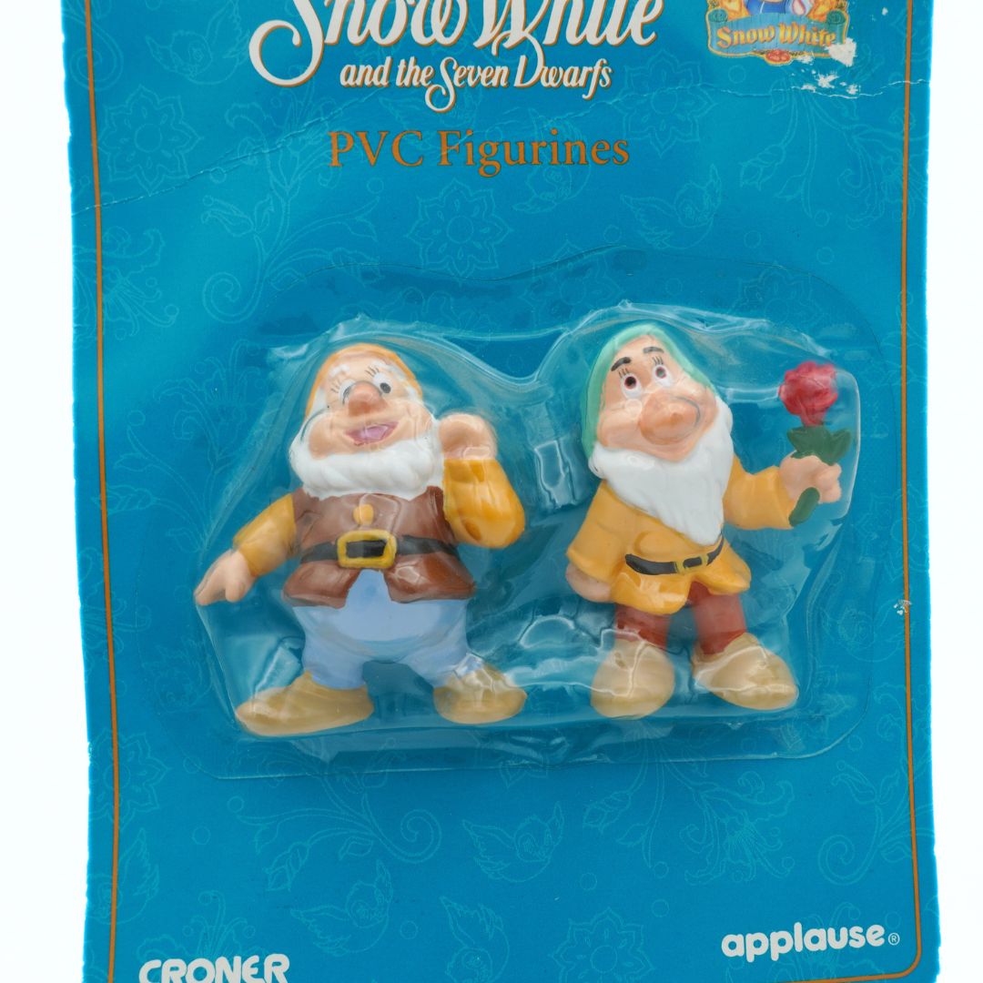 Two PVC figurines of dwarfs from 'Snow White and the Seven Dwarfs' in packaging with 'Applause' branding.