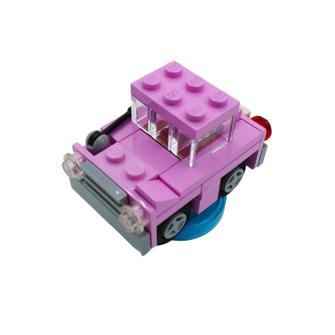 A small pink toy car built from interlocking blocks, shown on a plain white background. The car has a pink body, a pink roof, gray wheels, clear windows, a gray front bumper area, and a blue base.