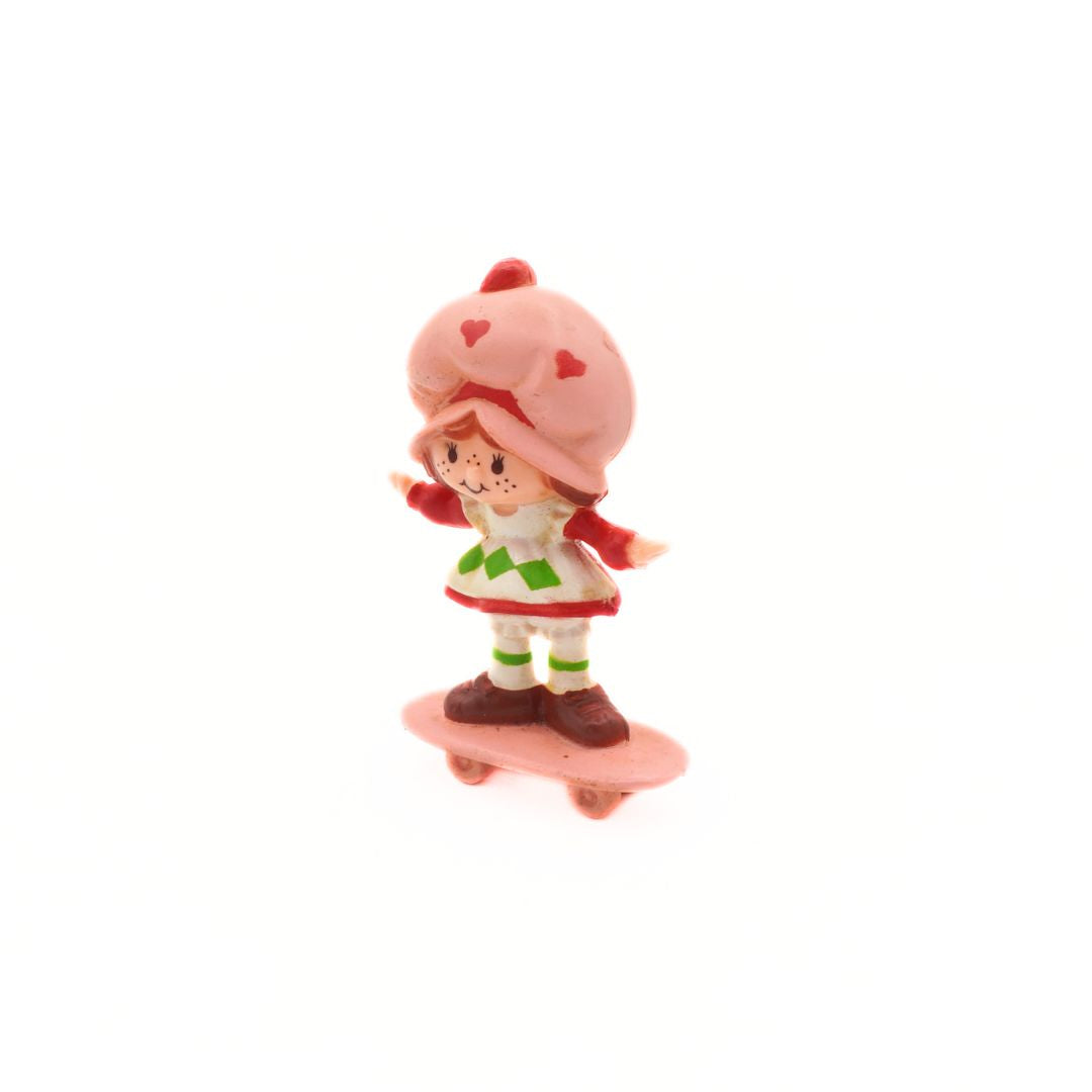 Toy figure of a character with a pink hat and skirt on a white background