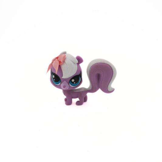 Small purple and white figurine with a pink bow on a white background
