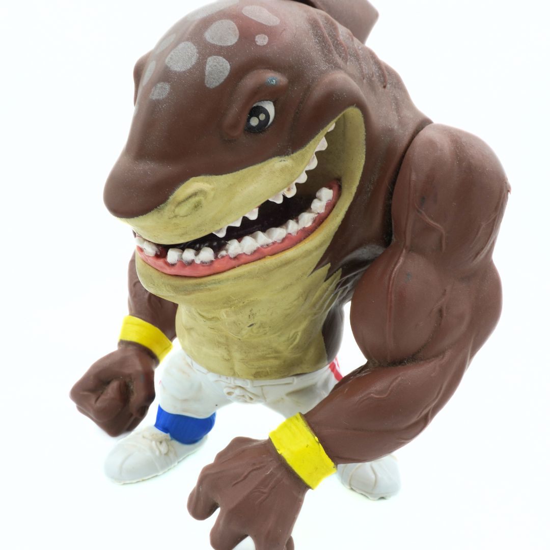 Toy figure of a muscular shark with a white background