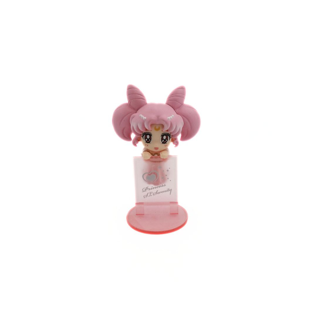 Front on photo of a mini figurine of the Sailor Moon Character Small Lady Serenity balancing on a translucent pink wall