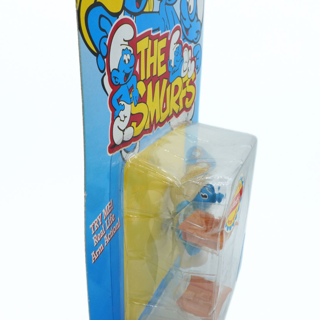 Toy figure in packaging with Smurfs branding on a white background
