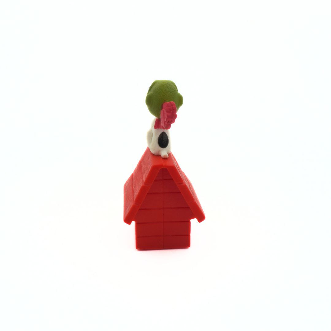 Snoopy toy on a red doghouse with a white background