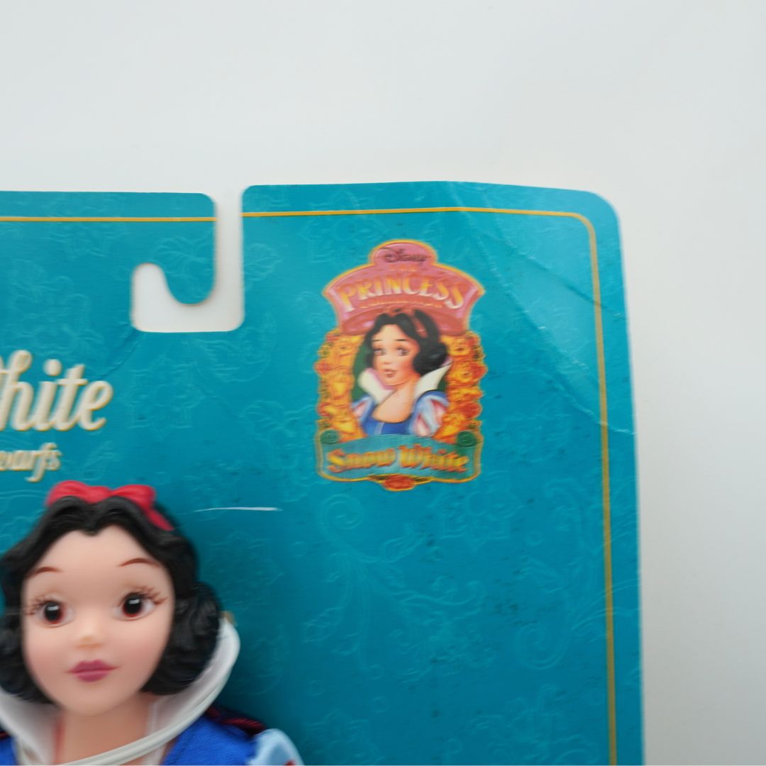 Snow White toy figure on a blue packaging background with Disney Princess logo.