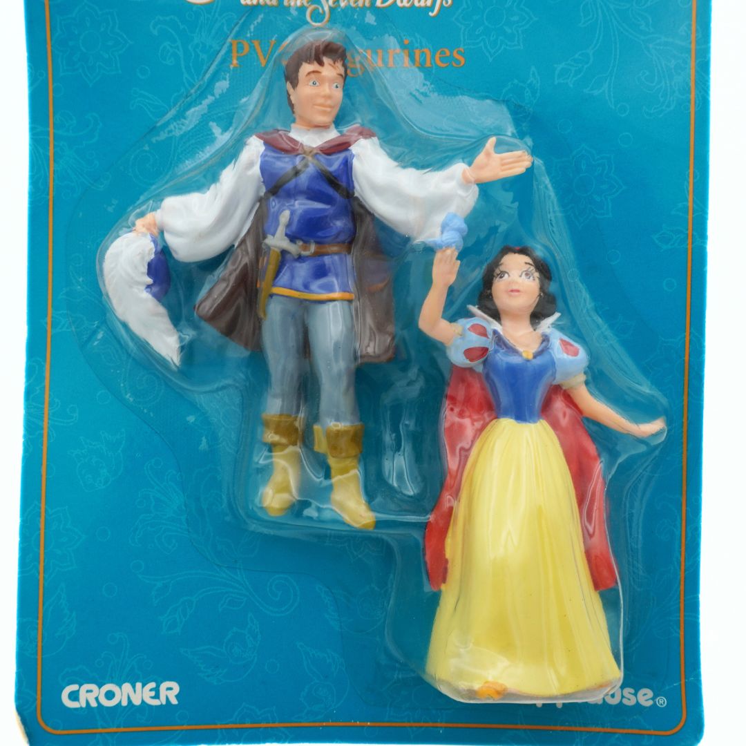 Two Disney figurines of a prince and princess in packaging on a blue background with 'Croner' and 'Applause' branding.
