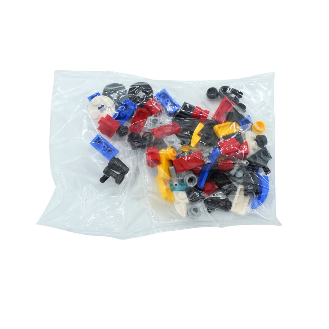 A clear plastic bag filled with assorted small building block pieces in black, red, blue, yellow, and white, photographed on a plain white background.