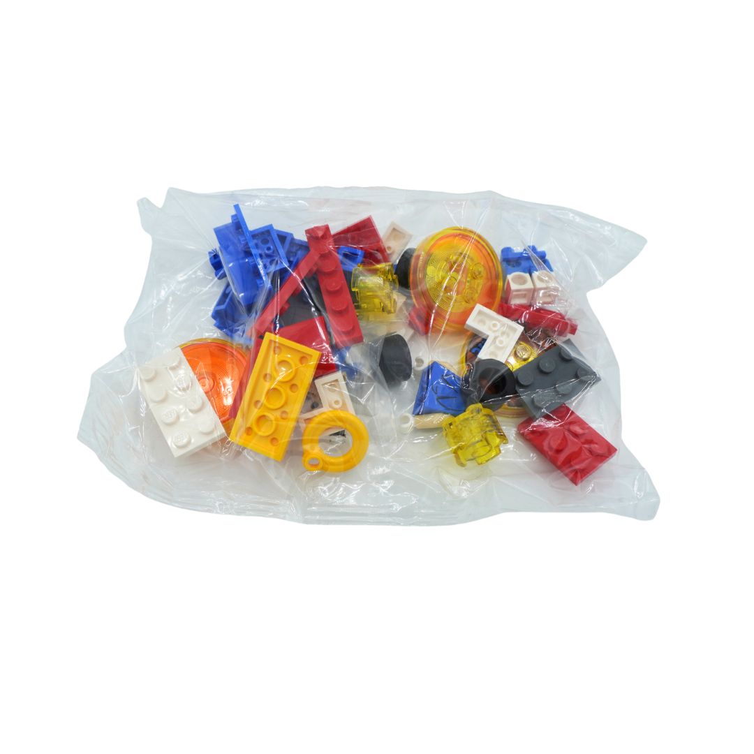 A clear plastic bag filled with assorted small multicolored toy building blocks and connectors, photographed on a plain white background.