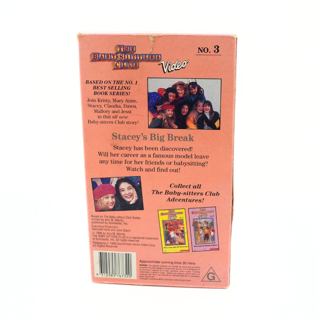Back cover of a VHS video case for 'The Baby-Sitter Club: Stacey's Big Break', showing the peach-colored cardboard packaging with printed text, photos of people, and two small movie cover thumbnails at the bottom.