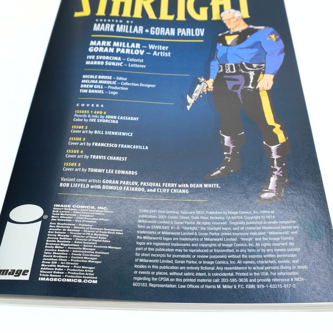 A close-up of a comic book cover or printed publication page with the title 'Starlight' at the top, creator names Mark Millar and Goran Parlov, and a large illustrated figure in a blue and yellow costume on the right side.