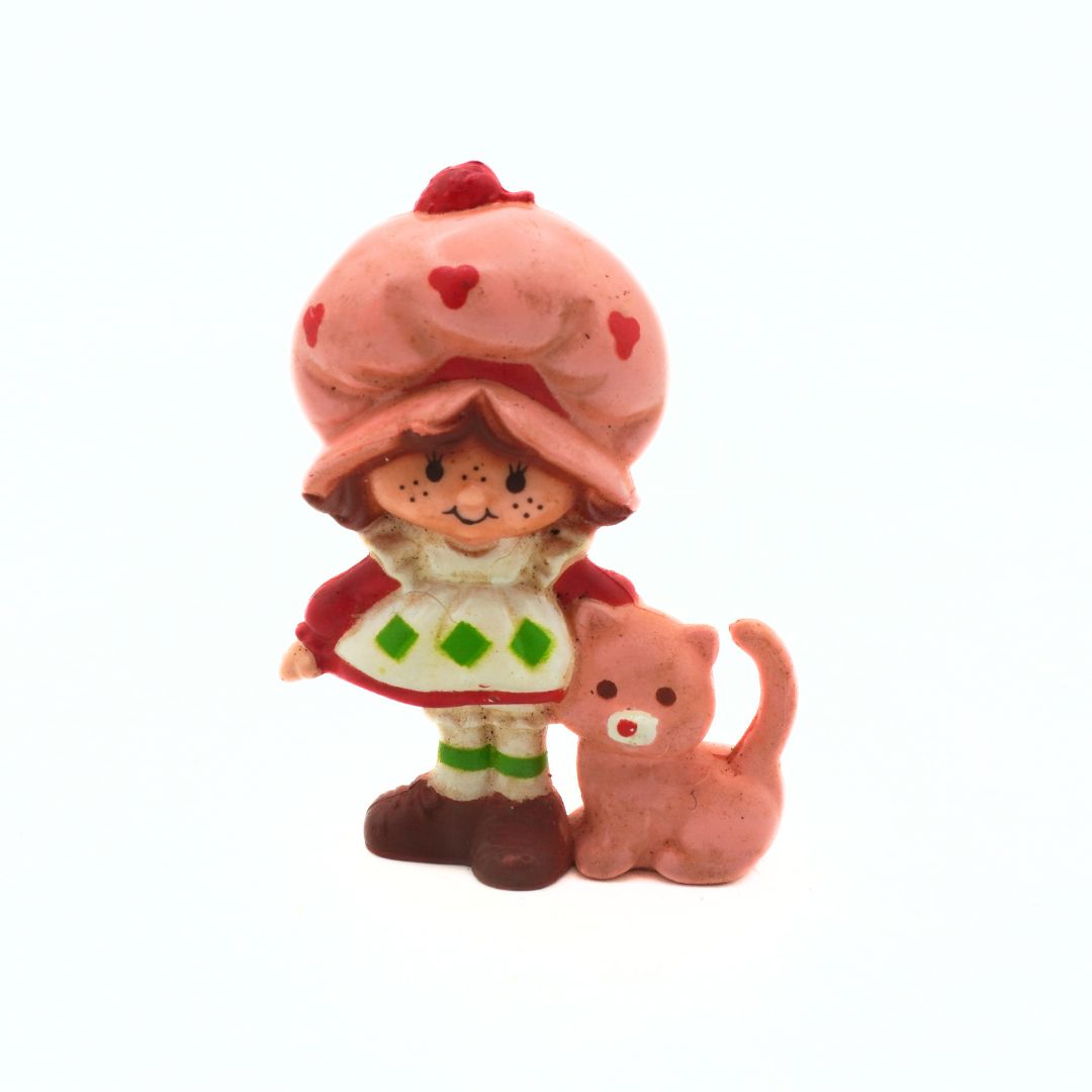 Toy figure of a character with a pink hat and a cat on a white background