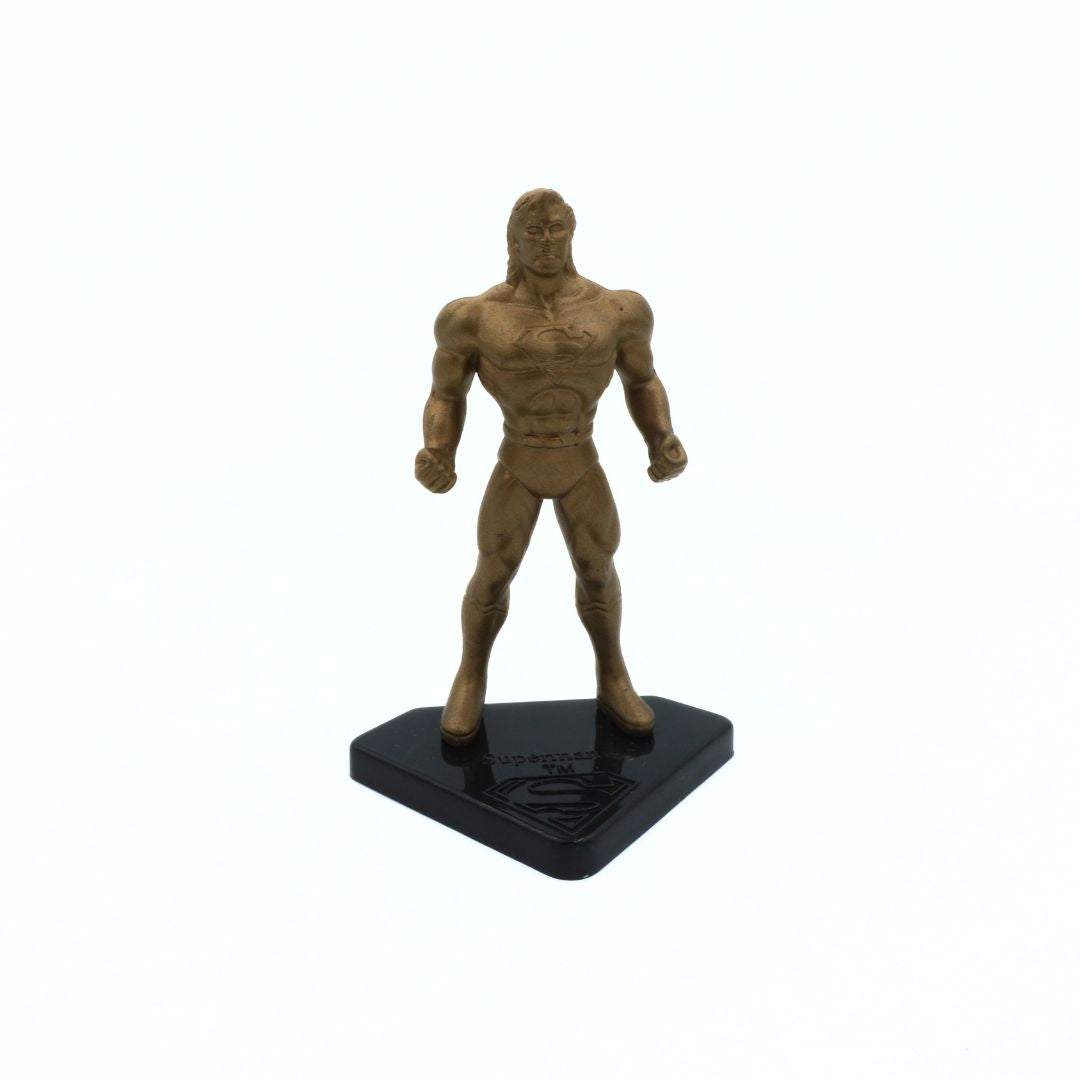 Bronze-colored superhero figure on a black base against a white background
