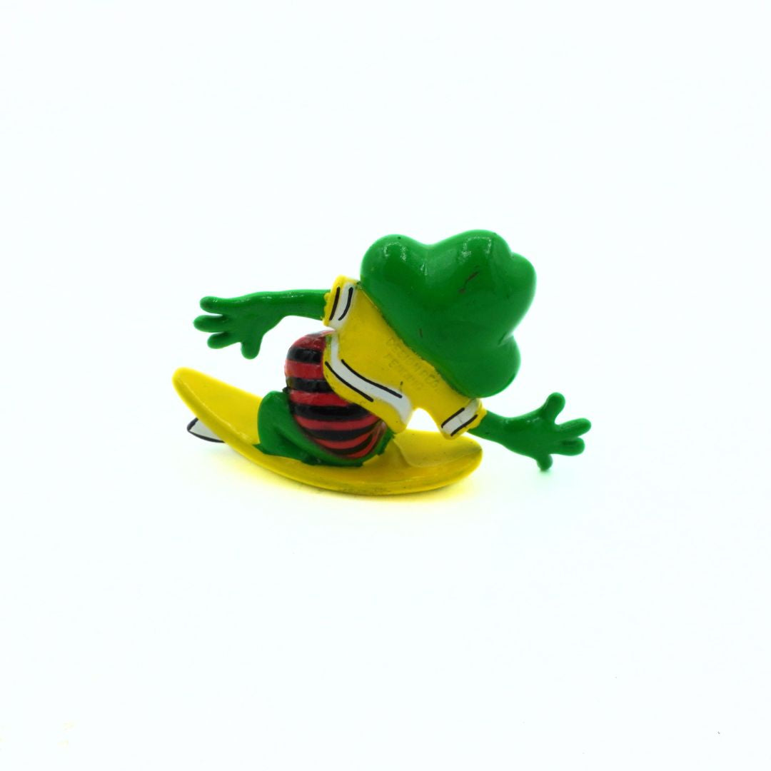 Toy frog on a yellow surfboard with a white background