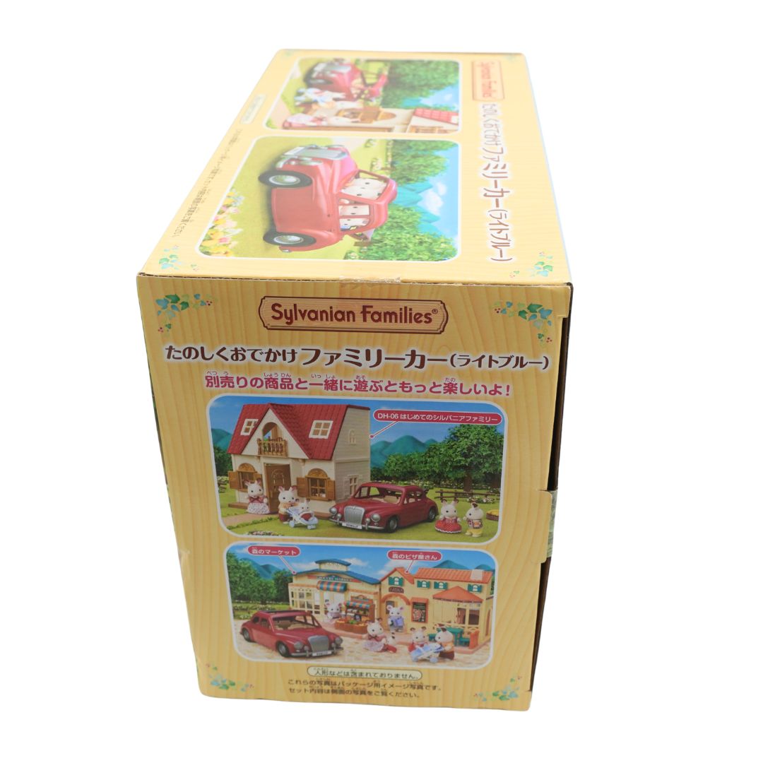 A cardboard box for the Sylvanian Families Family Car set, featuring Japanese text and colorful illustrations of a red car and miniature houses on a light wood-grained box.