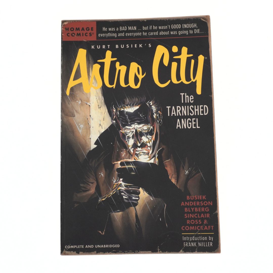 Astro City: The Tarnished Angel comic book by Kurt Busiek, published by Homage Comics. The cover features a dark illustration of a masked figure holding a gun, with the title 'Astro City' in large yellow font.