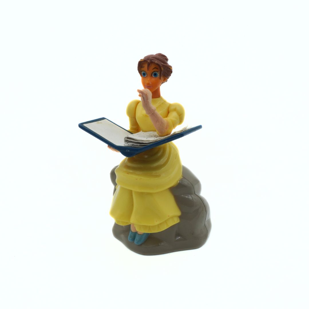 Figurine of a character in a yellow dress holding a book on a white background