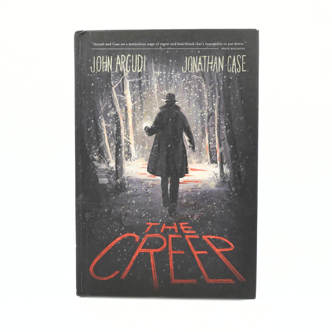 The Creep book by John Arcudi and Jonathan Case, featuring a dark cover illustration of a figure walking through a snowy forest at night with red title text, shown on a plain white background.