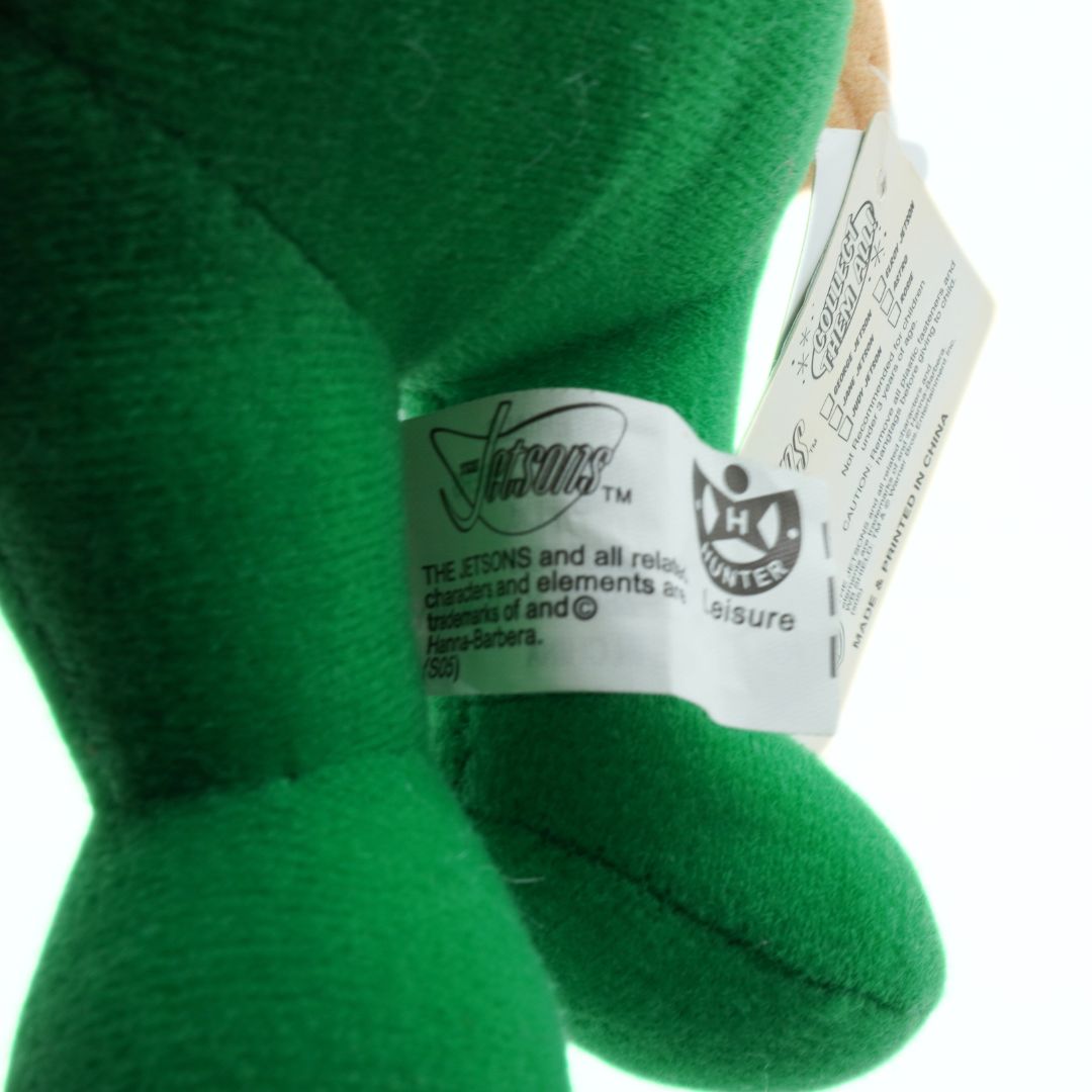 Green plush toy with a tag on a white background